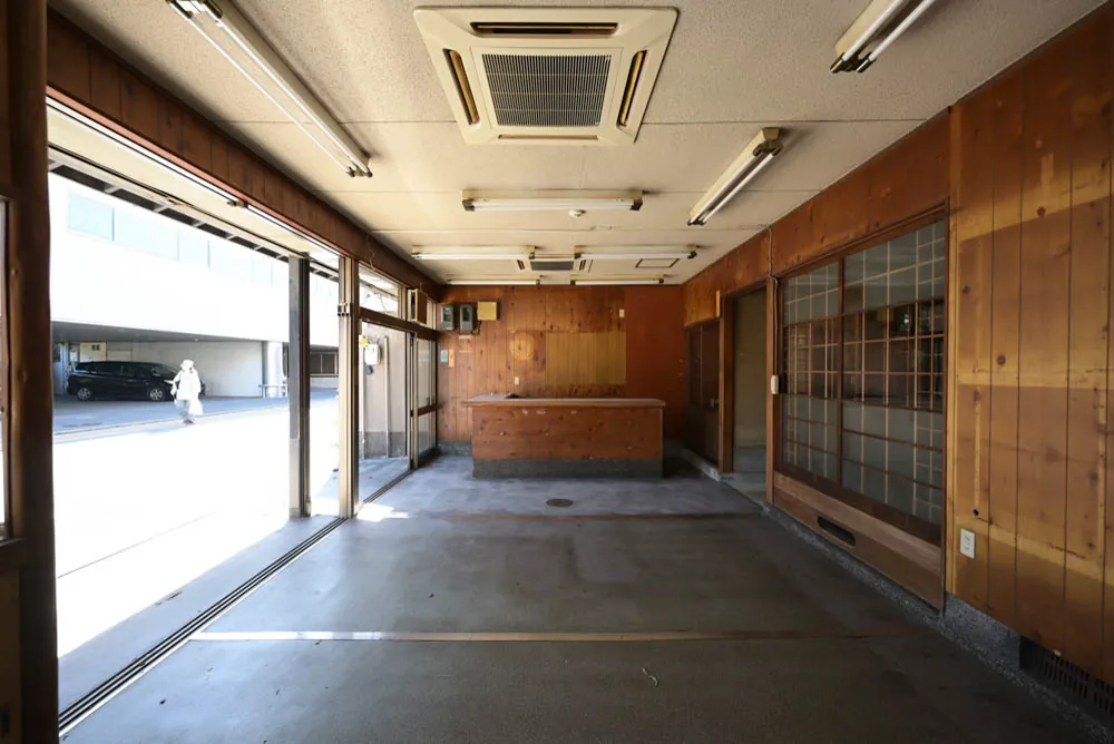 The front space as found: concrete floor, strip lights, the street beyond the glass.