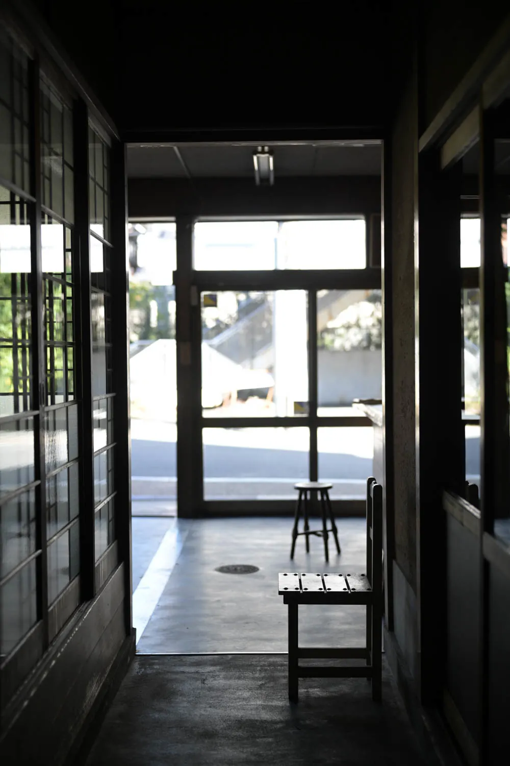 A dark hallway opening onto the bright street through glass doors.